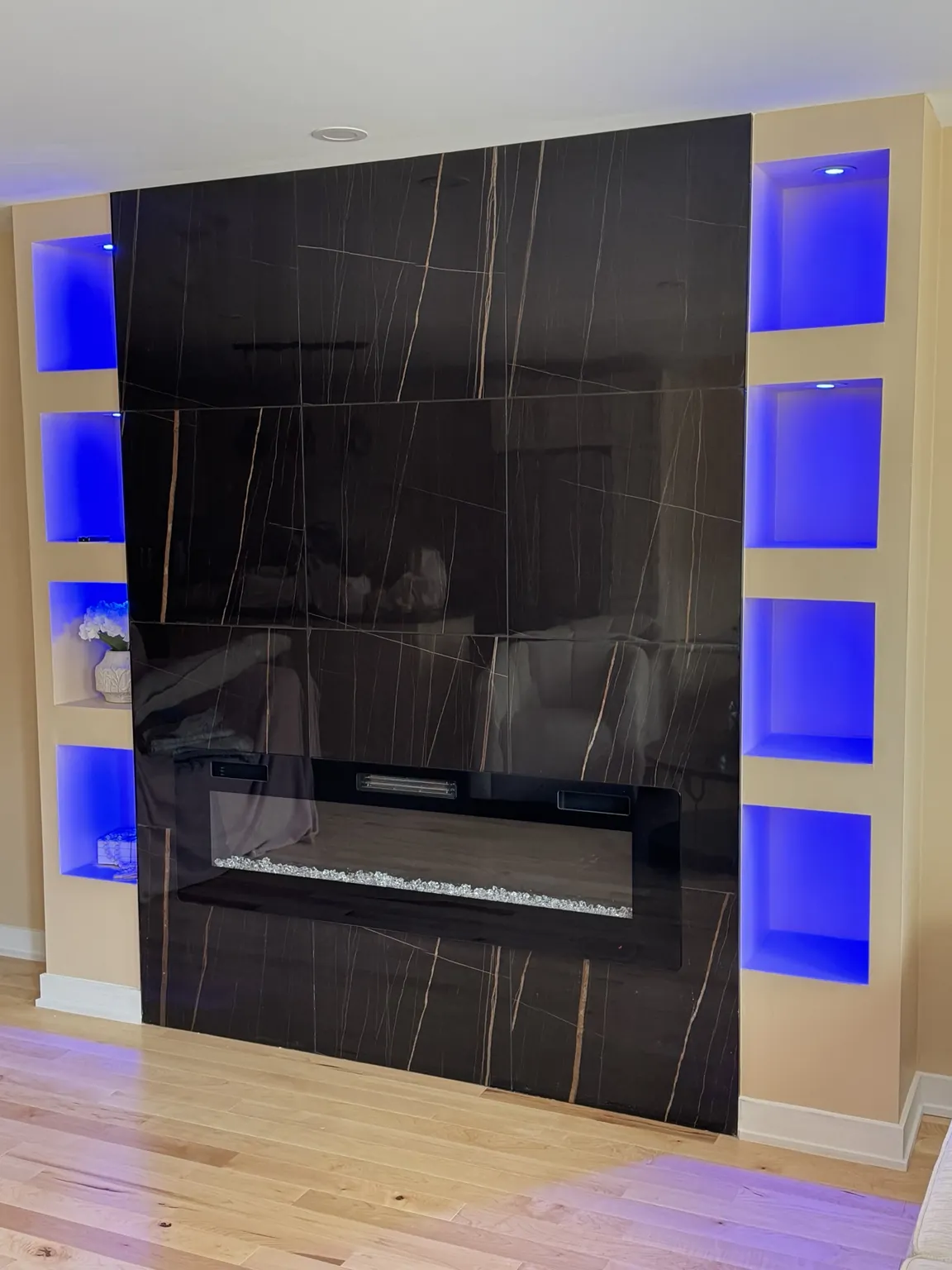 Black tiled fireplace surround with blue-lit shelves
