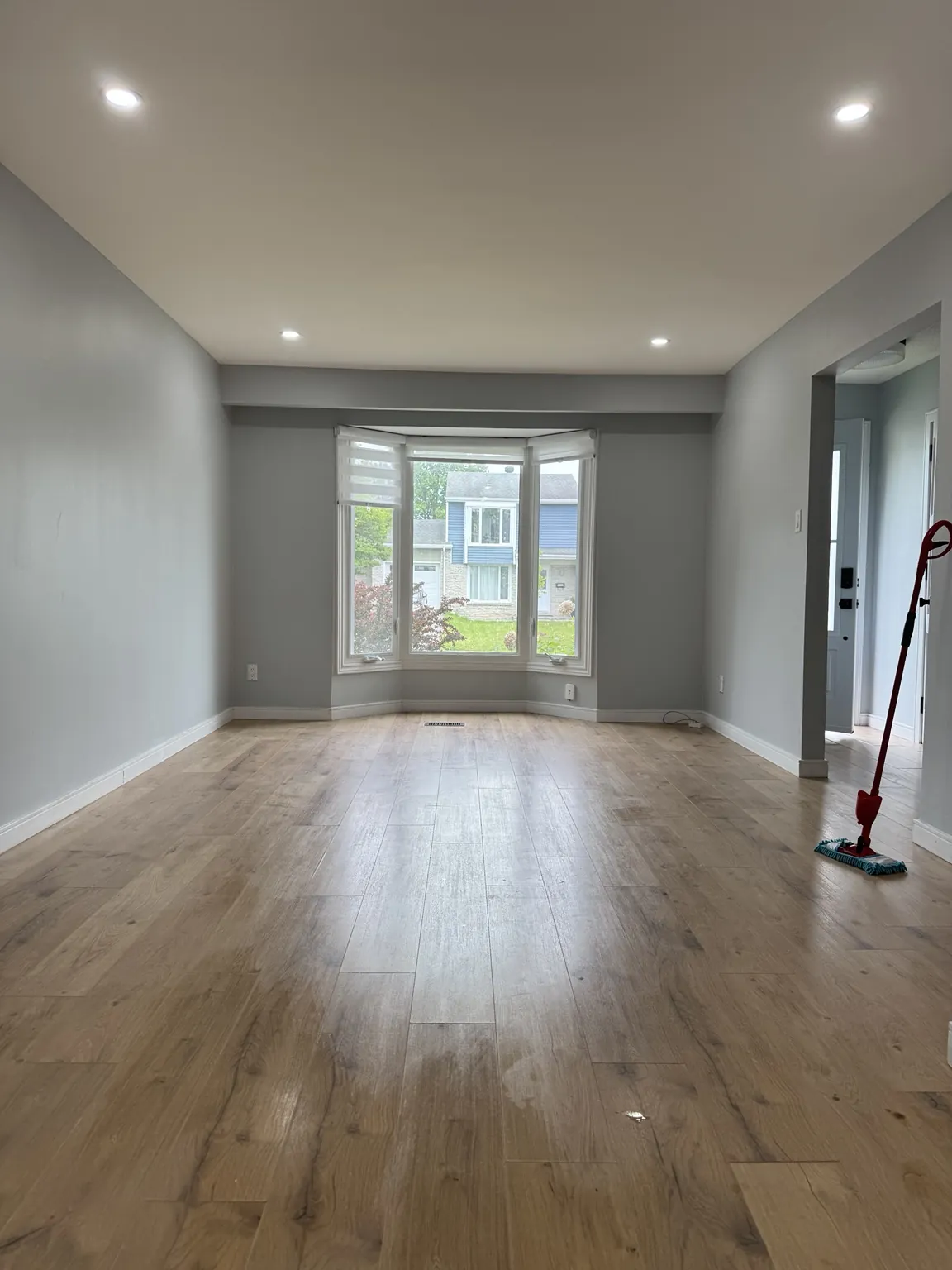 Renovated empty room with gray walls, plank flooring and bay window